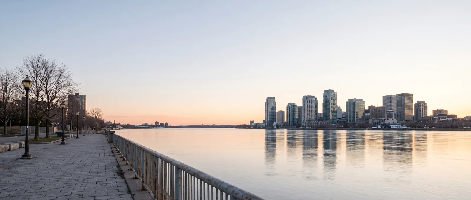 Generated scene: dawn over a wide river seen from an empty riverside promenade with lamp posts and a railing, a downtown skyline of glass towers across the water.